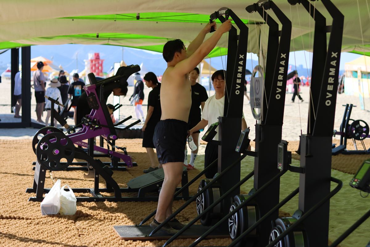 해변에 설치된 운동 기구로 운동하는 비치짐 참가자들