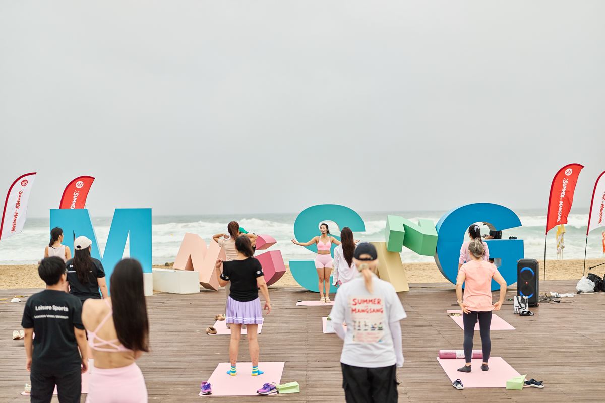 해변 데크에서 매트를 펴고 함께 움직이는 웨이브 클래스 참가자들